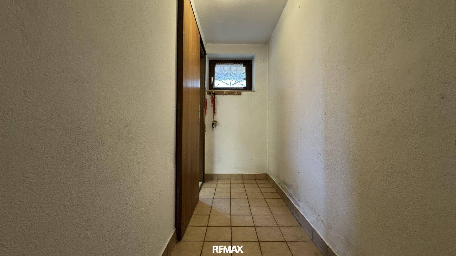 Kleiner Abstellraum mit Fliesenboden und einem Fenster für Tageslicht.