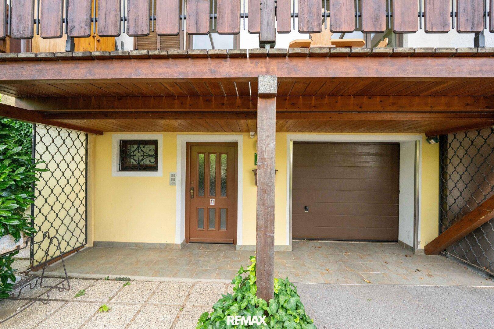 Eingangsbereich des Hauses mit Haustür und integrierter Garage im Erdgeschoss.