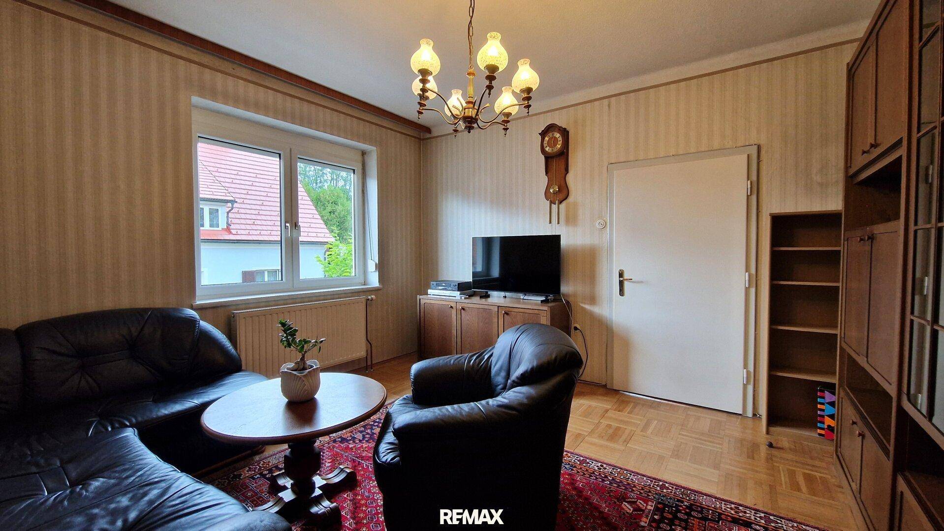 Wohnzimmer mit Parkettboden, Ledersofa und traditionellem Kronleuchter, strahlt Gemütlichkeit aus.