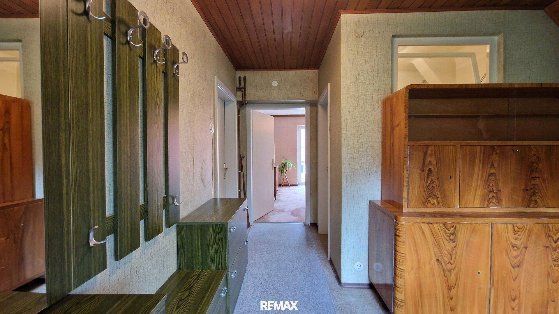 Langer Flur mit Garderobe, Holzmöbeln und Zugang zu weiteren Räumen im Obergeschoss.