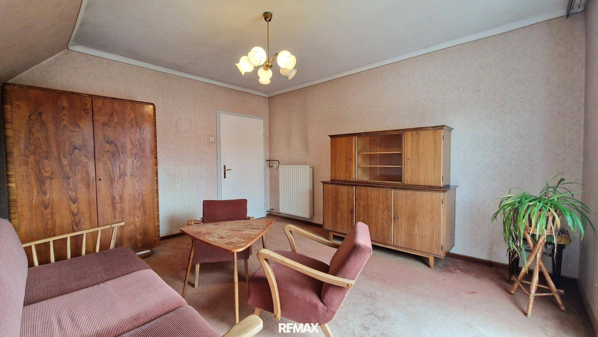 Dachgeschoss-Wohnzimmer mit traditionellen Möbeln, Dachschräge und Teppichboden, sehr geräumig.