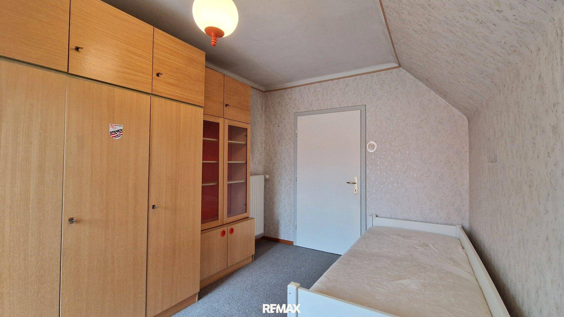 Schlafzimmer im Dachgeschoss mit Einzelbett, Einbauschränken und Dachschräge, praktisch eingerichtet.