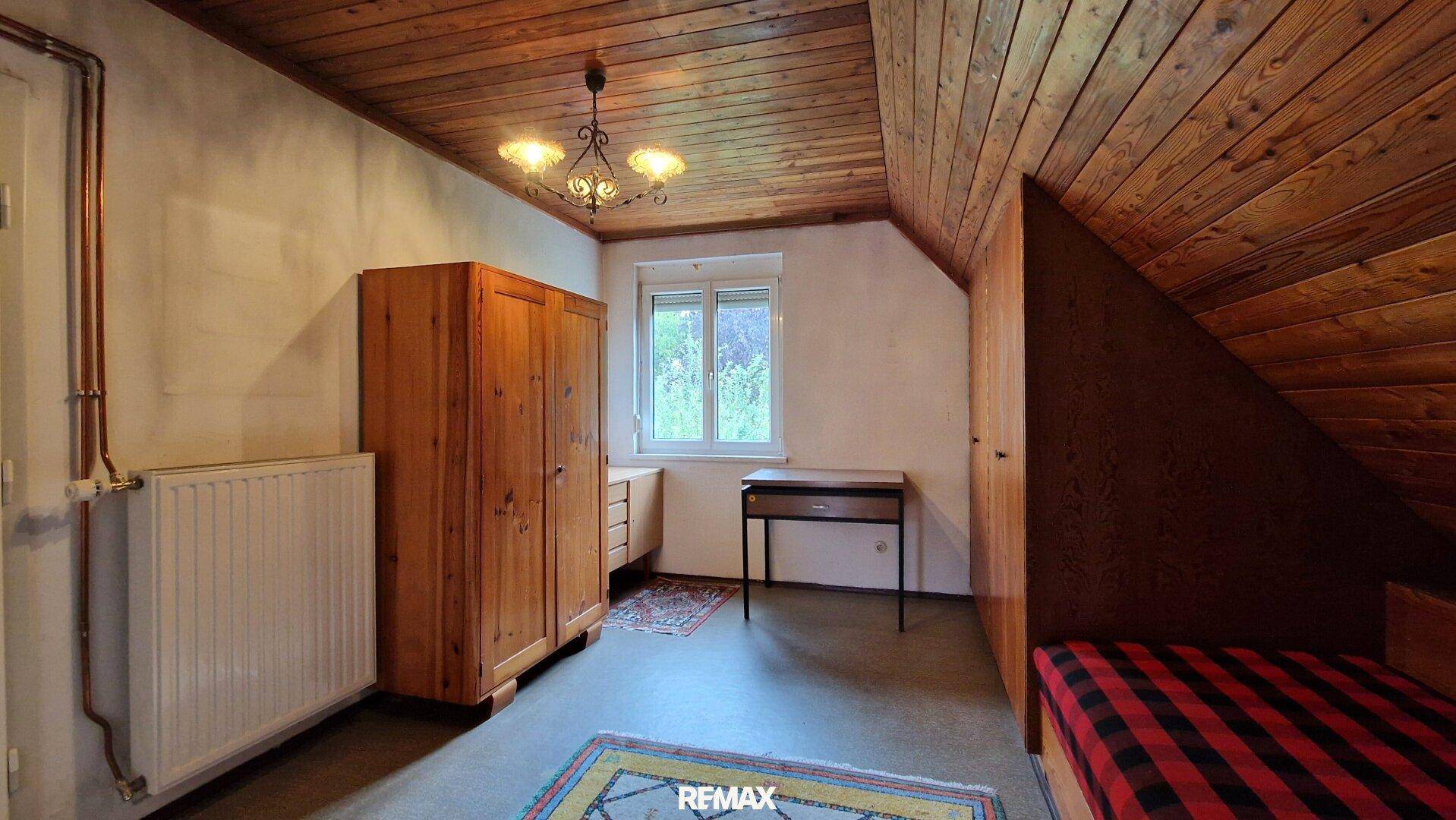 Rustikales Dachgeschoss-Schlafzimmer mit Holzdecke, Dachschräge und Holzmöbeln, sehr gemütlich.