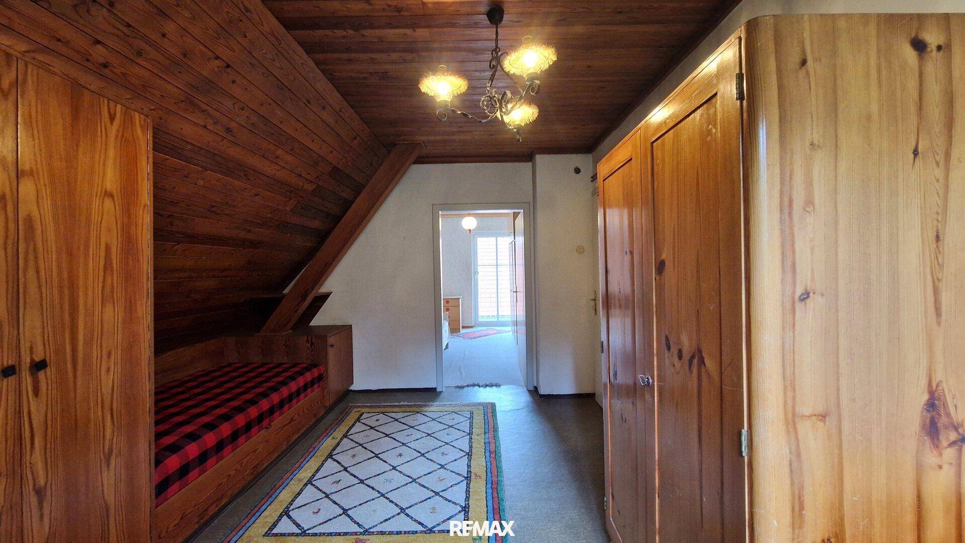 Dachgeschoss-Schlafzimmer mit Holzdecke, Dachschräge und Blick in den Flur, hell und freundlich.