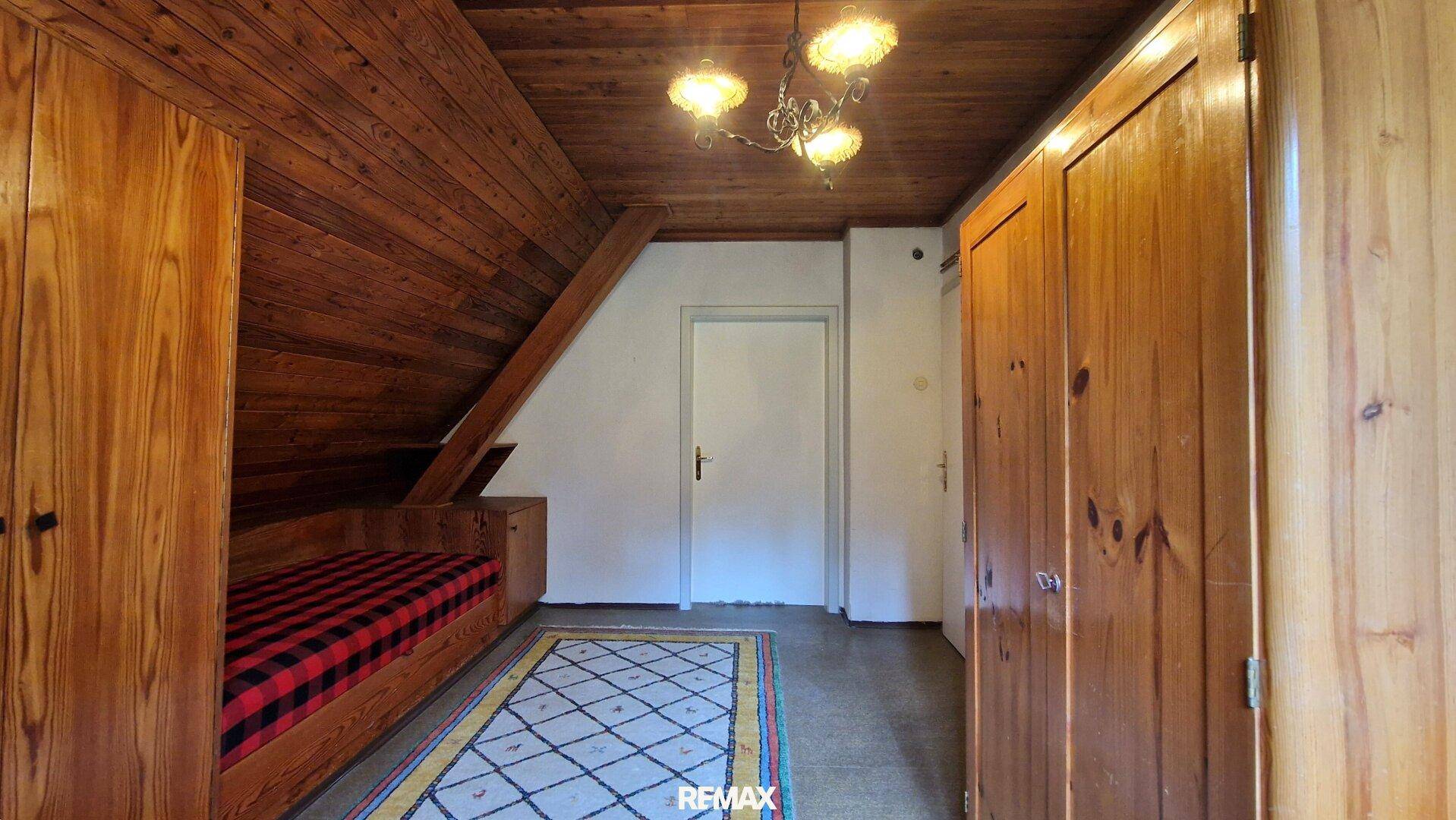 Gemütliches Dachgeschoss-Schlafzimmer mit Holzdecke, Dachschräge und Holzschränken, viel Stauraum.