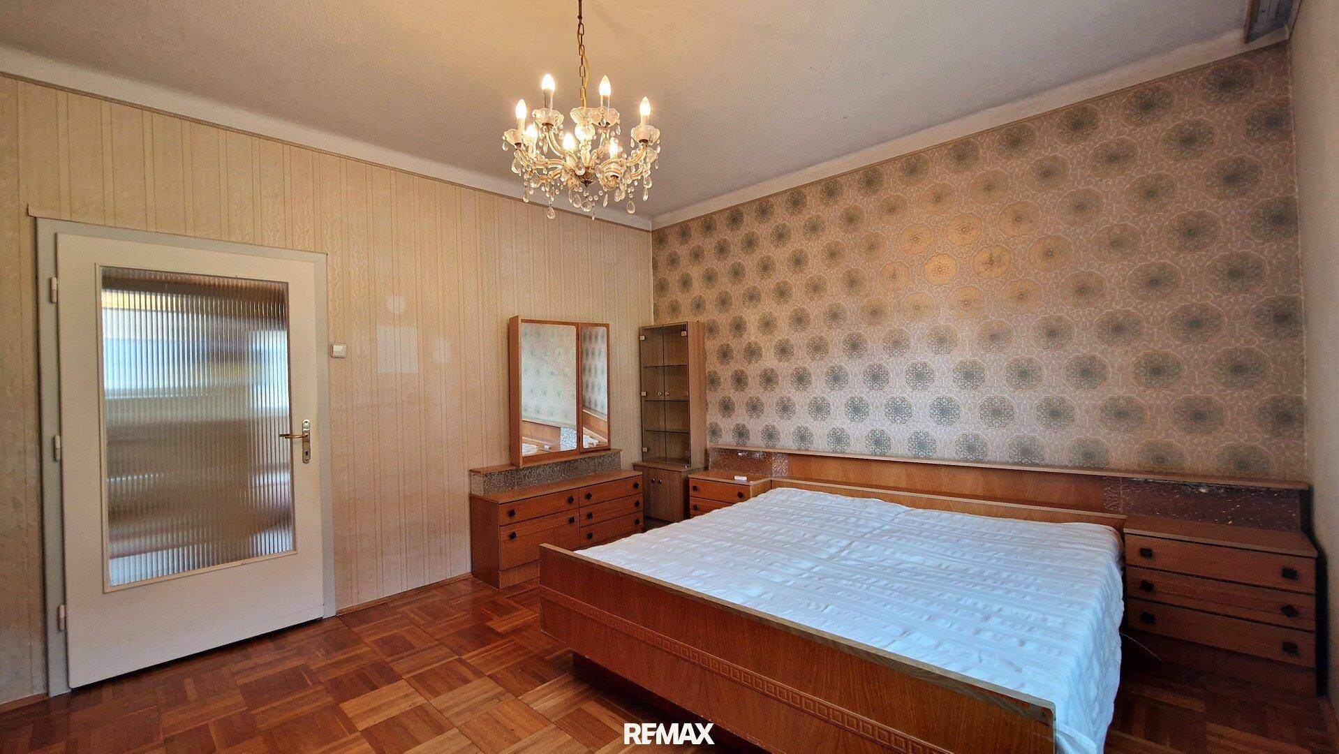 Geräumiges Schlafzimmer mit Parkettboden, Doppelbett und traditionellen Möbeln für Komfort.