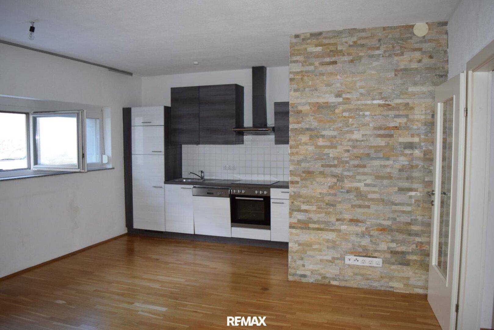 Moderne Küche mit Holzboden, zweifarbigen Schränken und einer dekorativen Steinwand.