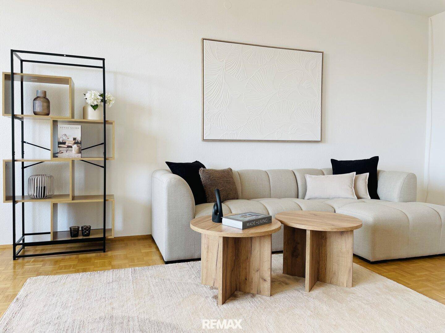 Gemütliches Wohnzimmer mit beigem Sofa, Holztischen und modernem Regal.