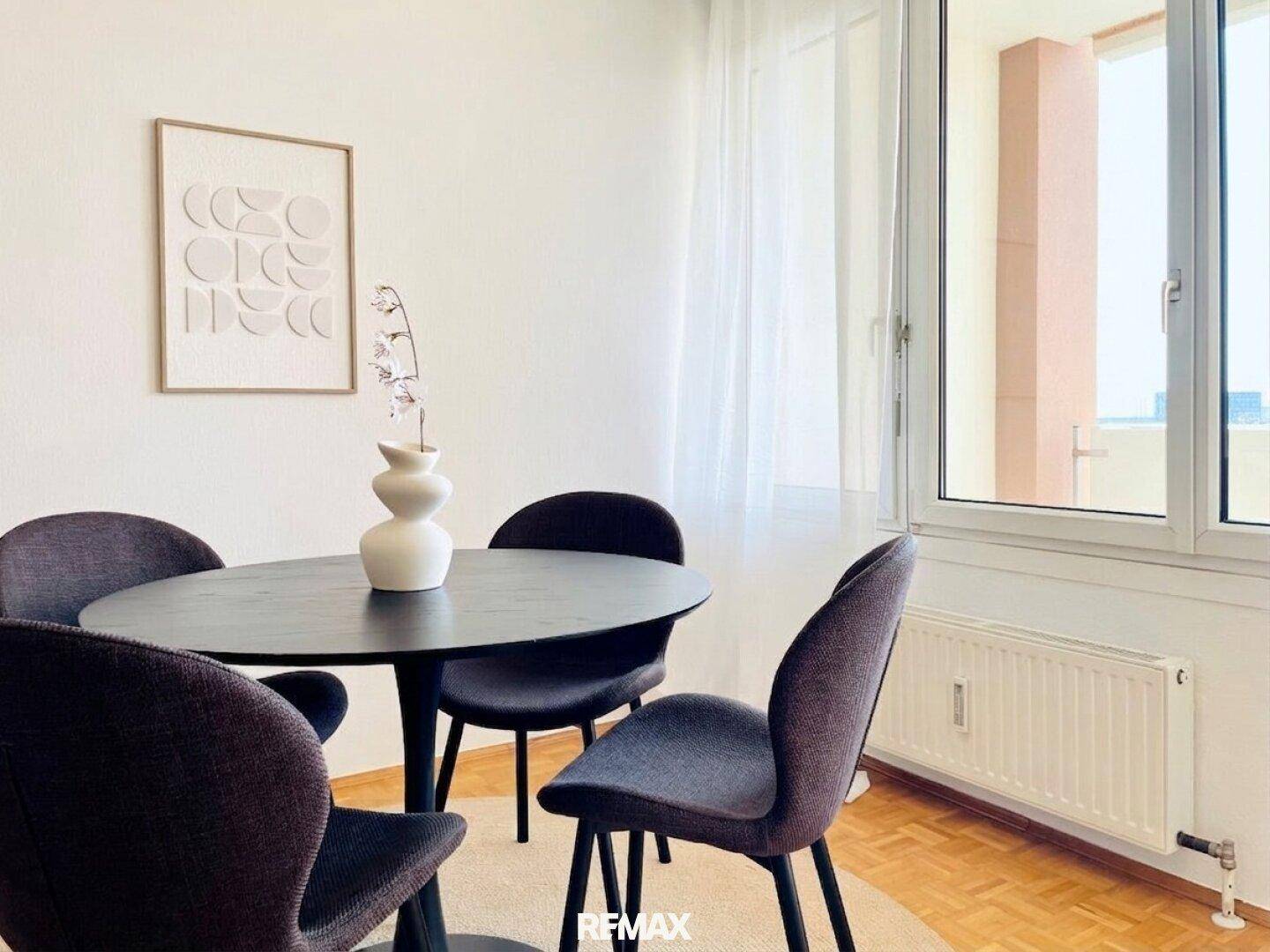 Heller Essbereich mit Fenster, Heizkörper und Zugang zu einem Außenbereich.