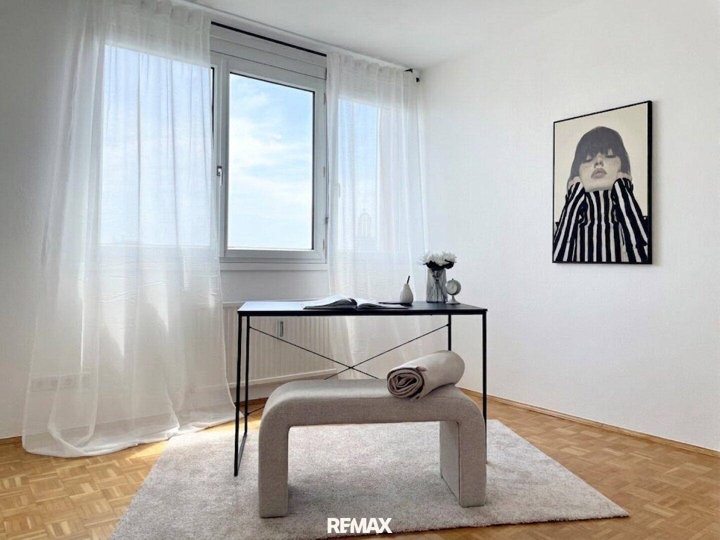 Moderner Arbeitsplatz mit Schreibtisch, Sitzbank und großem Fenster.