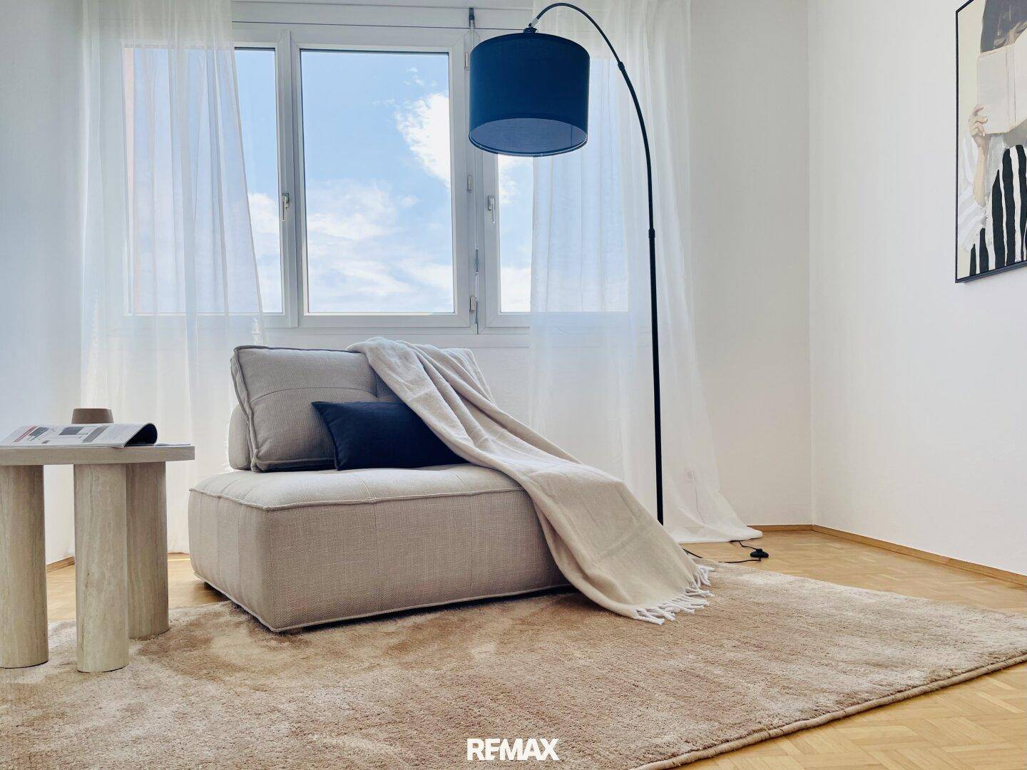 Gemütliche Leseecke mit Sessel, Stehlampe und großem Fenster.
