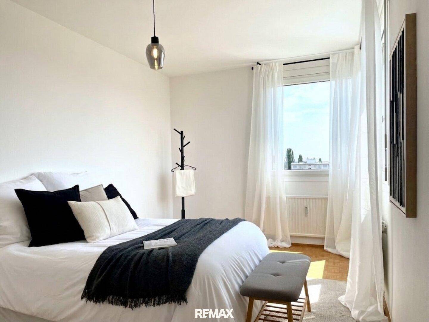Modernes Schlafzimmer mit Doppelbett, Parkettboden und viel Tageslicht.