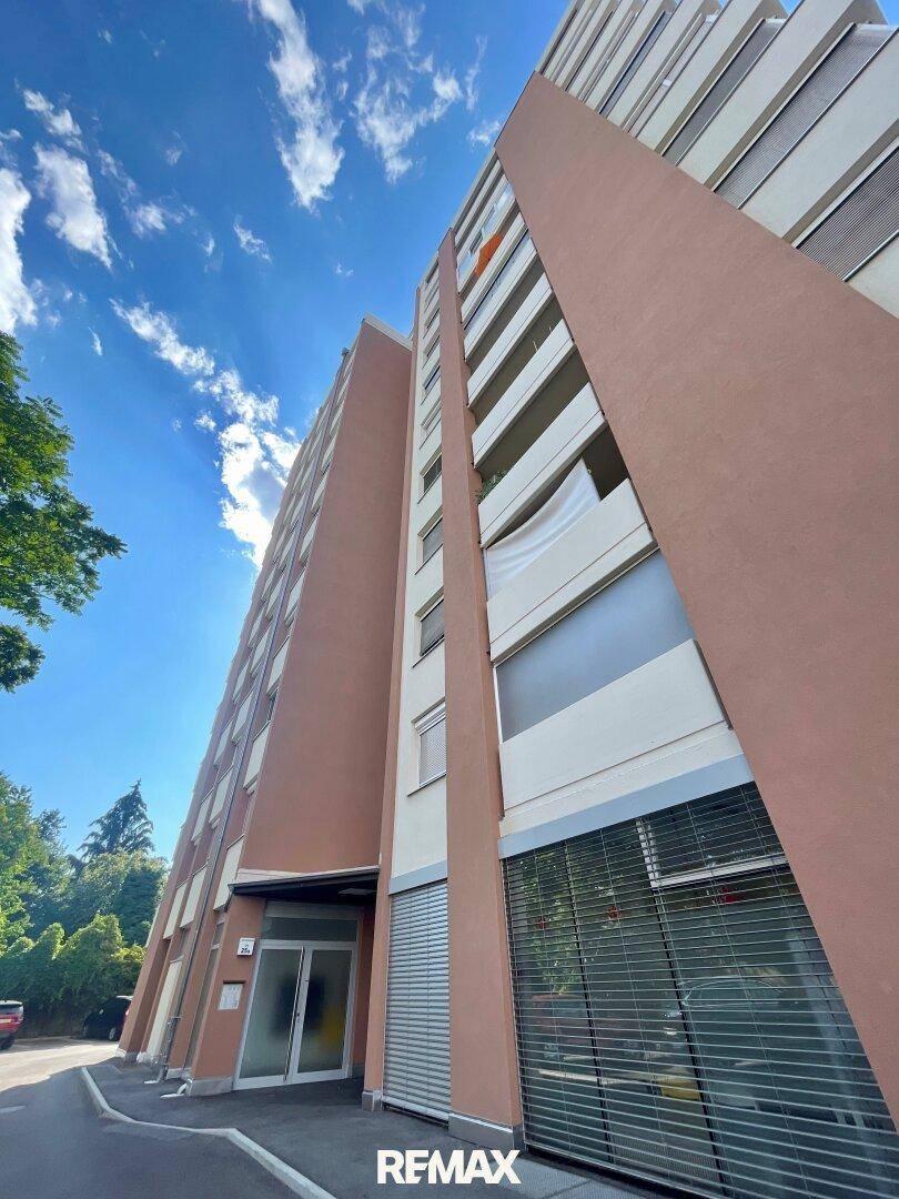 Hohes Wohngebäude mit moderner Fassade und vielen Balkonen unter strahlend blauem Himmel.