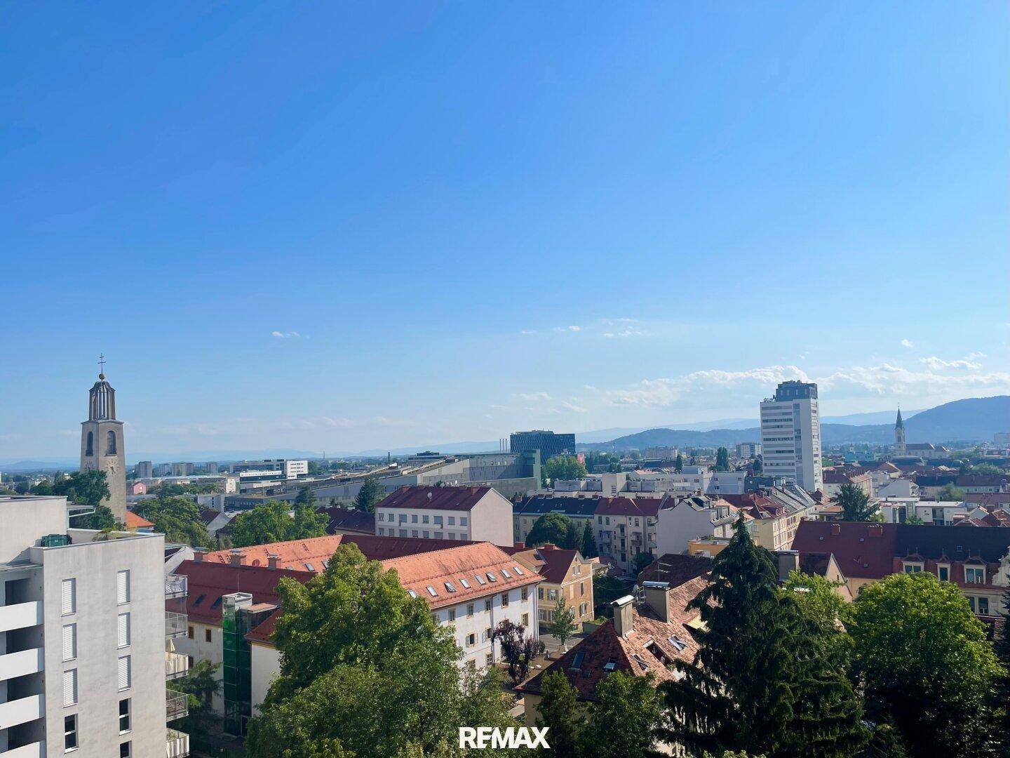 Panoramablick über die Stadt mit historischen Gebäuden, einem Kirchturm und weitem Horizont.