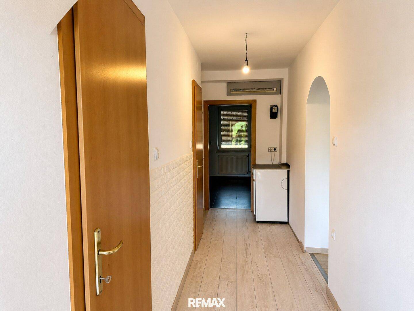 Heller Flur mit Laminatboden, Holztüren und Zugang zu weiteren Räumen.
