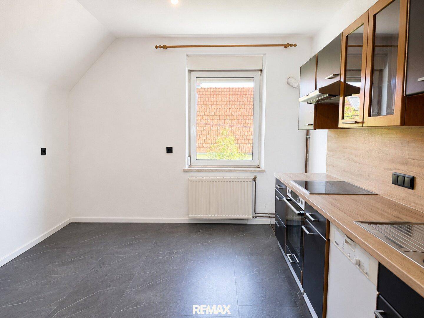 Moderne Küche mit dunklen Schränken, Holzarbeitsplatte und Fensterblick.
