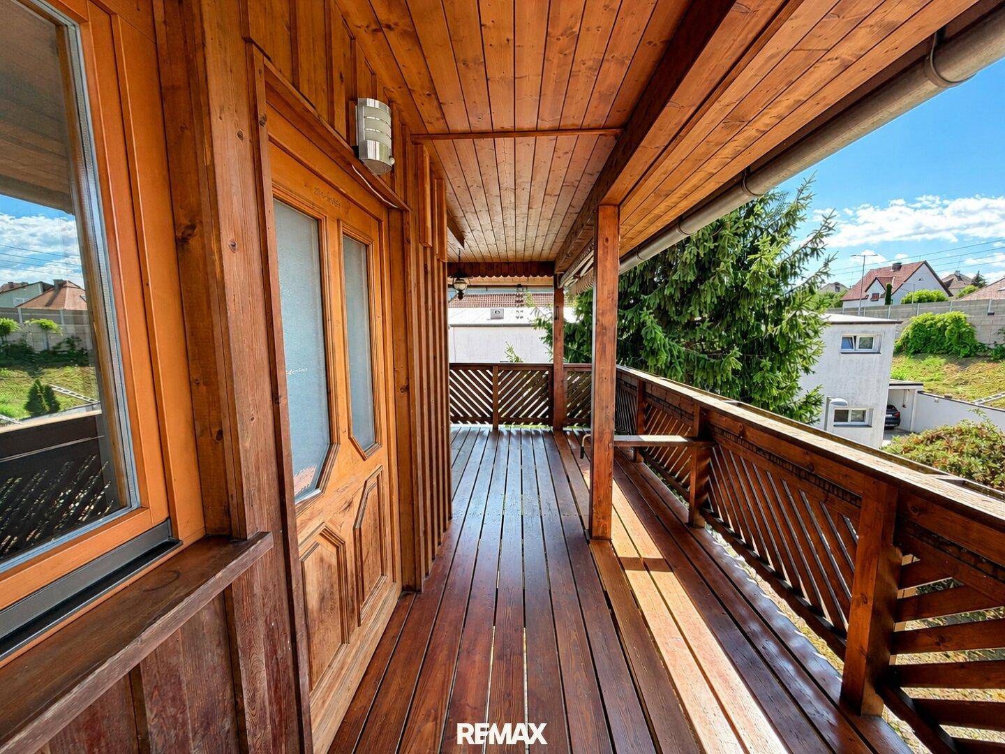 Langer Holzbalkon mit Geländer und Blick auf die Umgebung.