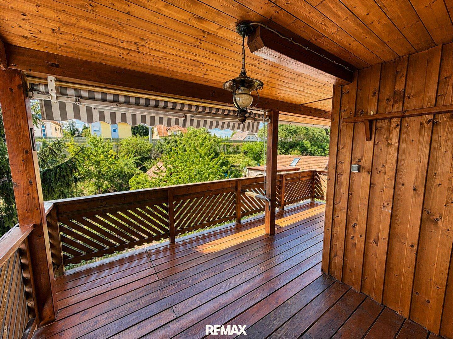 Geräumiger Holzbalkon mit Markise und weitem Blick ins Grüne.