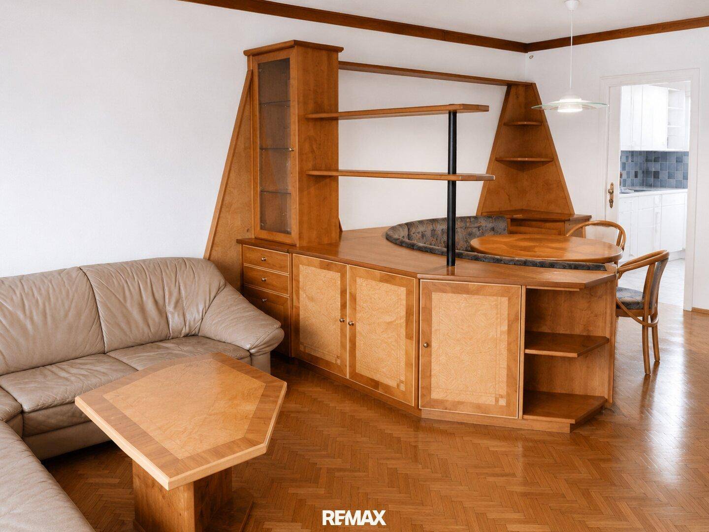 Wohn- und Essbereich mit maßgefertigten Holzmöbeln, Ledersofa und Parkettboden.