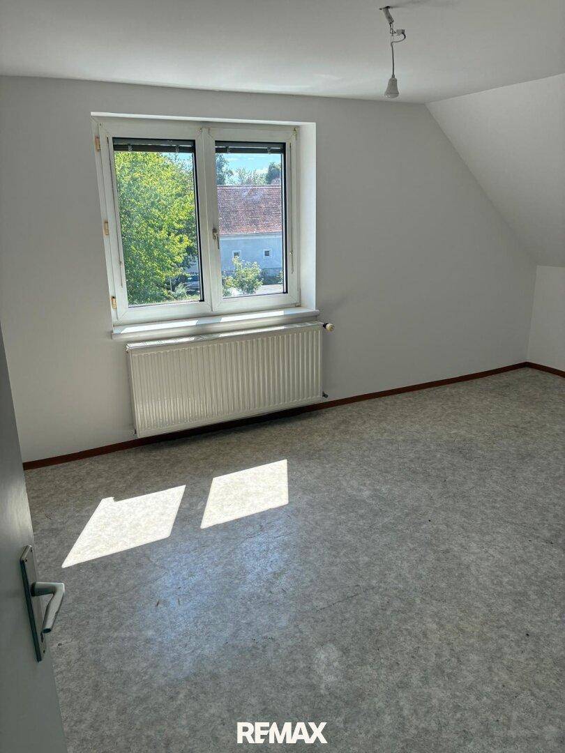 Heller Raum mit Vinylboden, großem Fenster und Heizkörper, der viel Tageslicht hereinlässt.