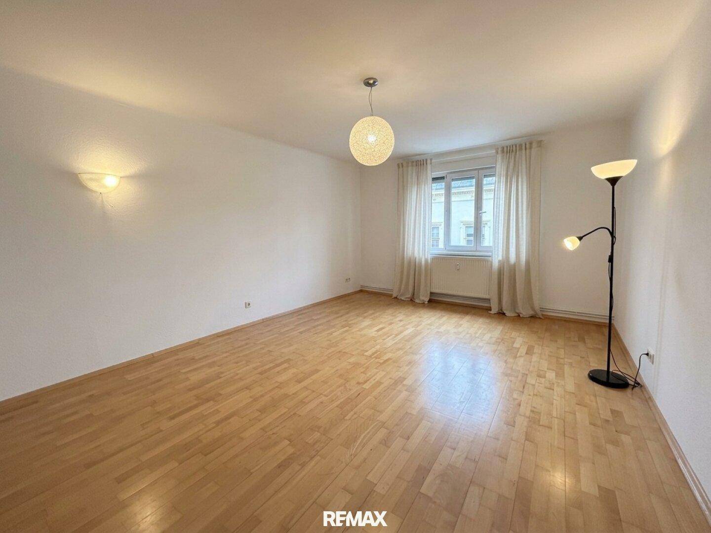 Geräumiges, unmöbliertes Wohnzimmer mit hellen Wänden und klassischem Parkettboden, bereit zur Gestaltung.