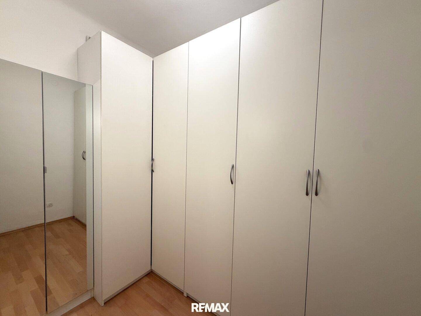 Schlafzimmer mit praktischen, weißen Einbauschränken und hellem Parkettboden für viel Stauraum.