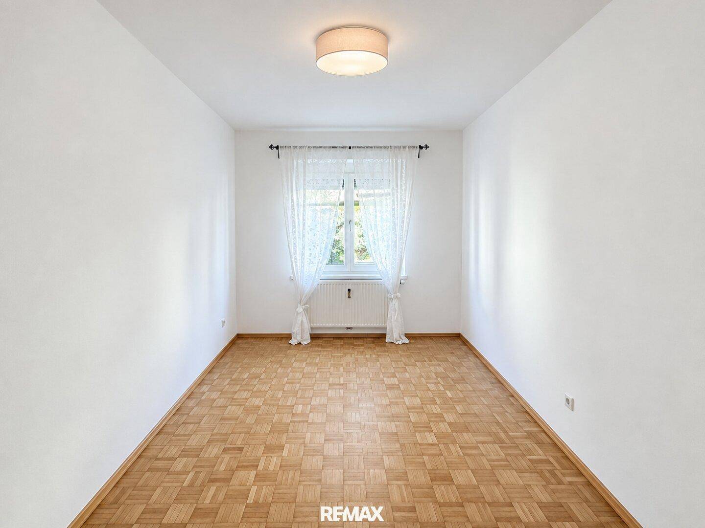 Leerer Raum mit hellem Parkettboden und Fenster, bereit zur individuellen Gestaltung.