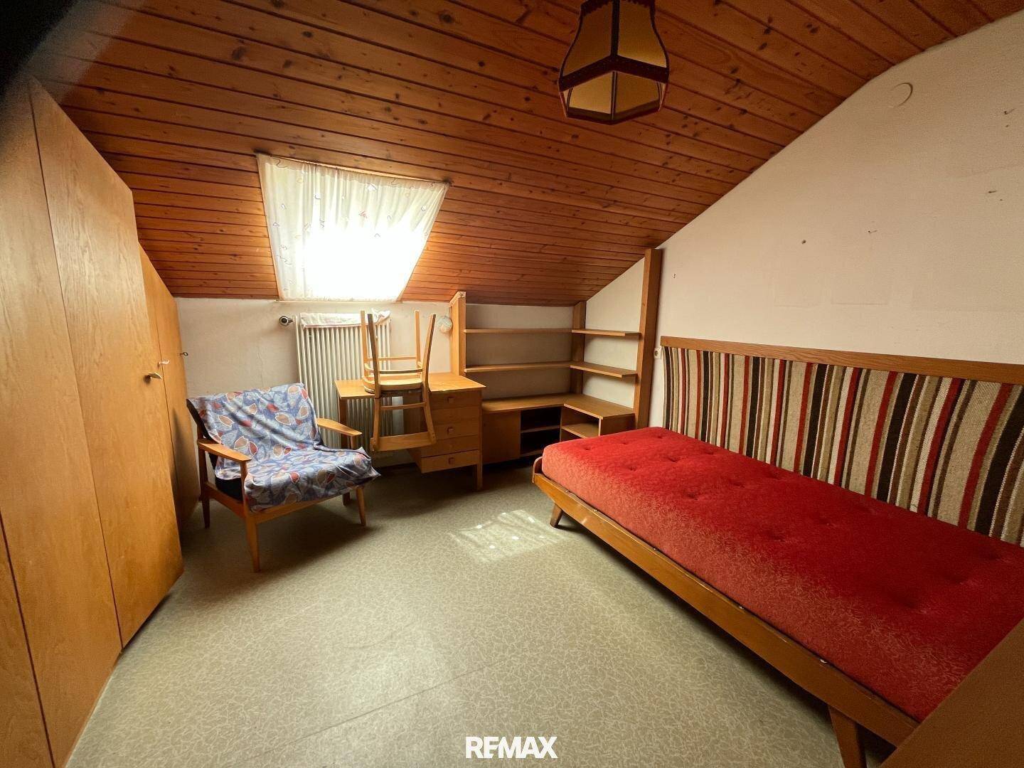 Schlafzimmer im Dachgeschoss mit Holzdecke, Dachfenster und Stauraum.