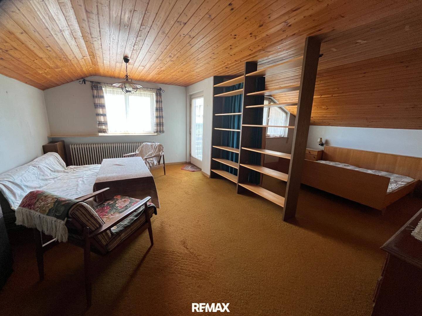 Geräumiges Schlafzimmer im Dachgeschoss mit Holzdecke und Teppichboden.