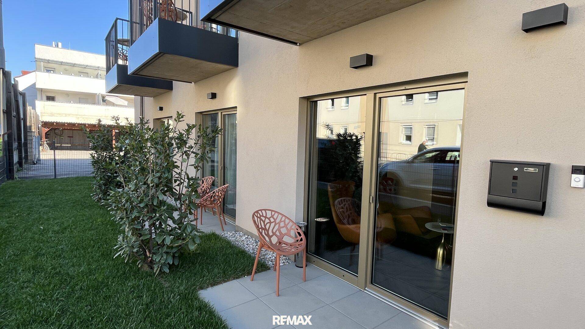 Kleine Terrasse im Erdgeschoss mit Gartenmöbeln und direktem Zugang zur Rasenfläche.