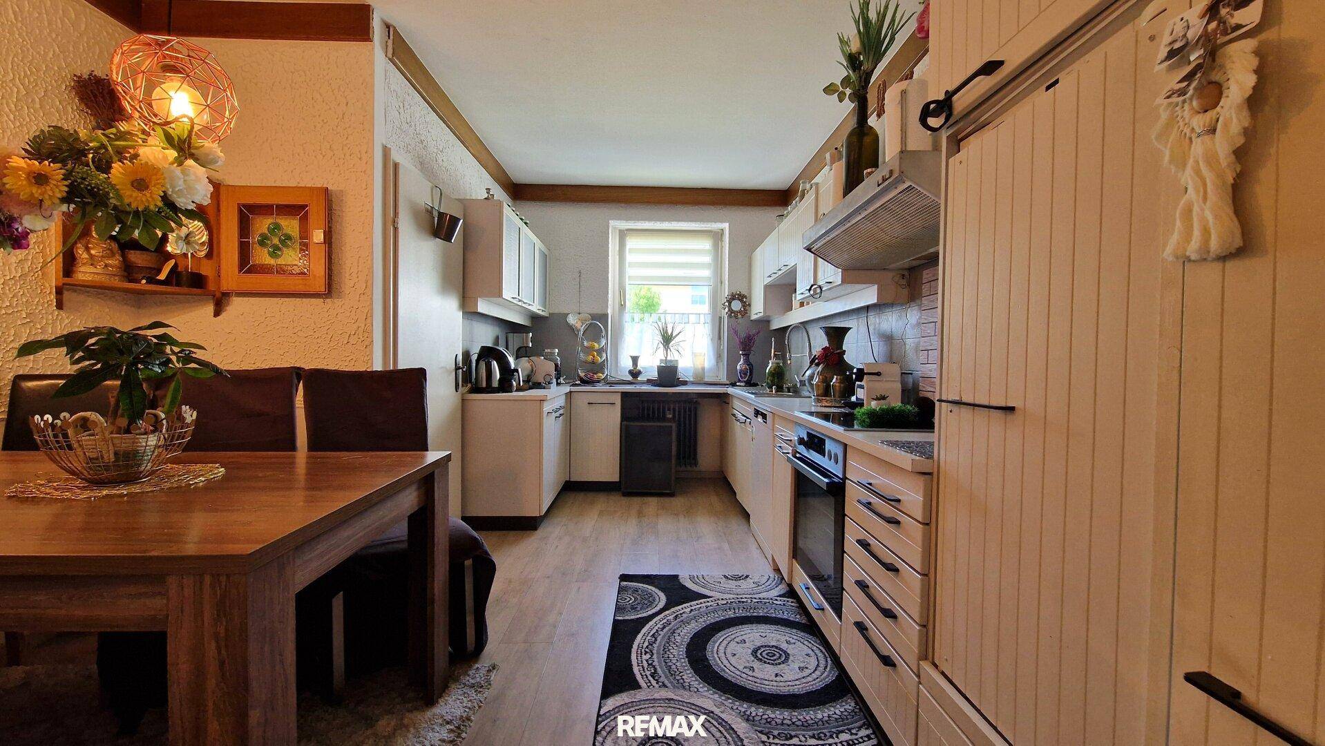 Funktionale Küche mit hellen Schränken, Holzoptikboden und Fenster.