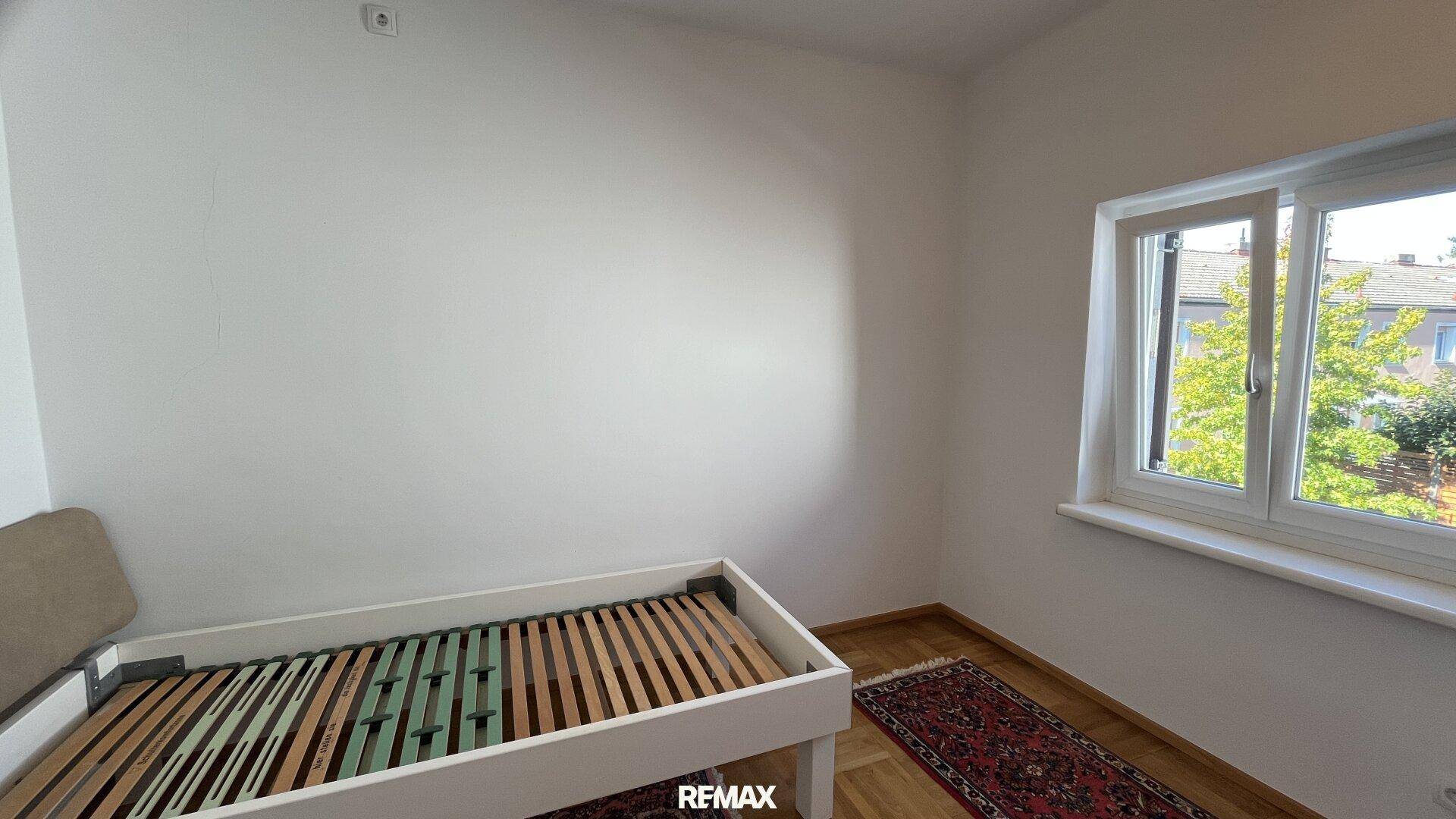 Schlafzimmer mit Parkettboden, Fenster und Platz für ein Einzelbett.