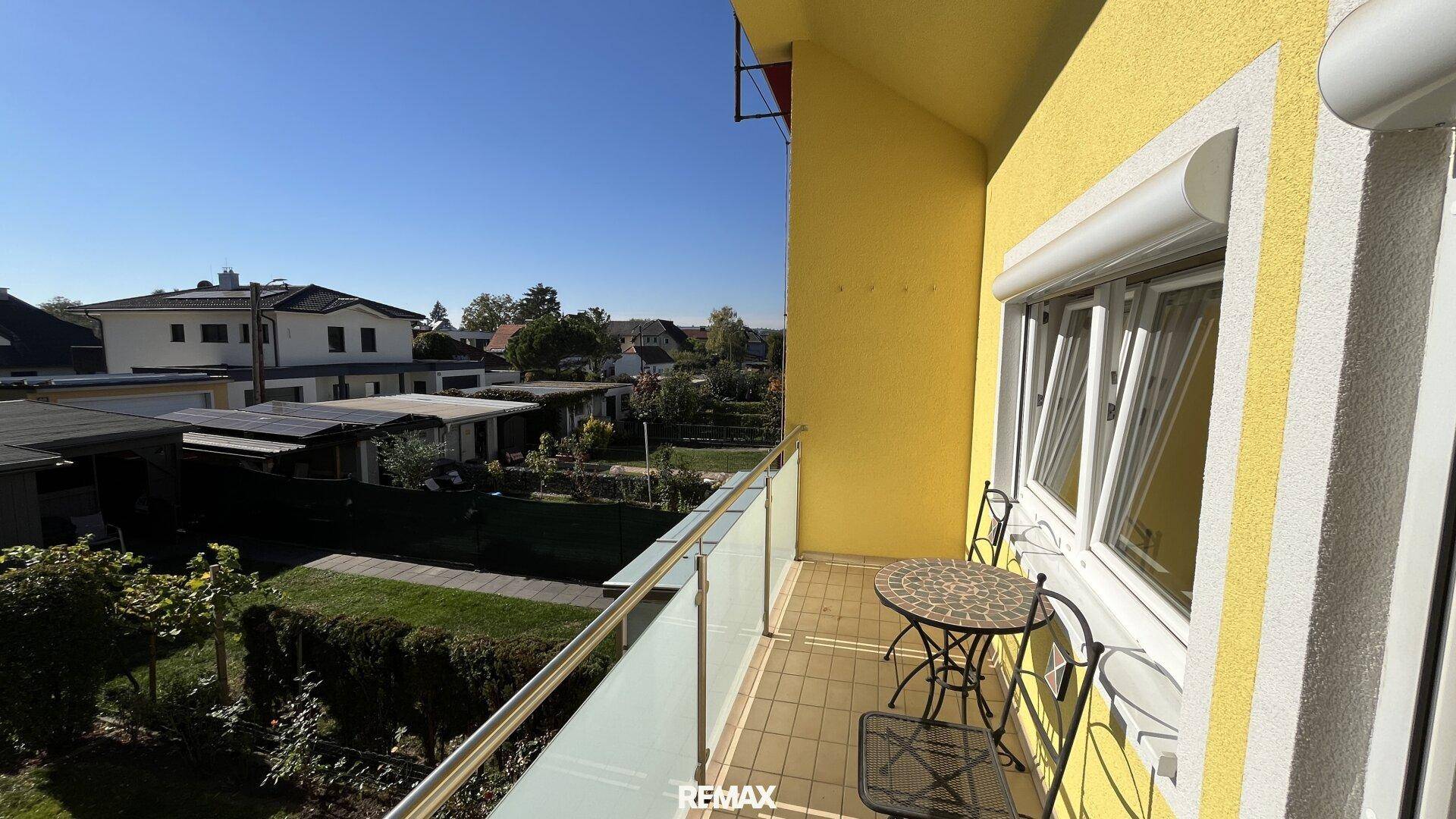 Kleiner Balkon mit Metallgeländer und Blick auf die umliegenden Häuser und Gärten.