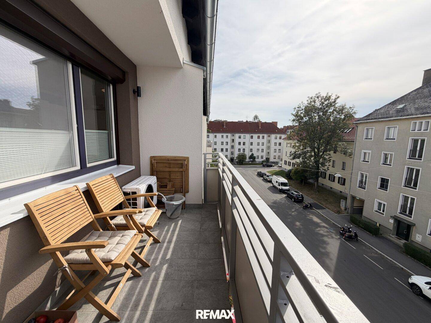 Balkon mit Sitzgelegenheiten und Blick auf die Straße und die gegenüberliegenden Gebäude.