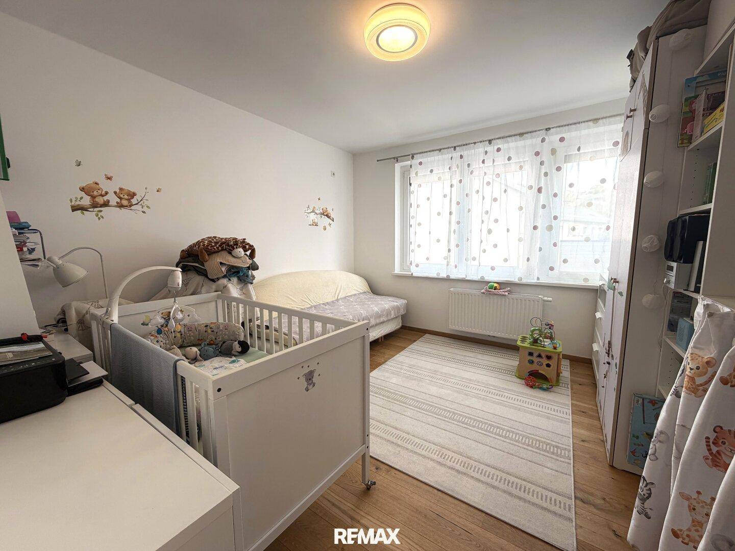 Kinderzimmer mit Babybett, Spielzeug und hellem Fenster, ideal für kleine Bewohner.