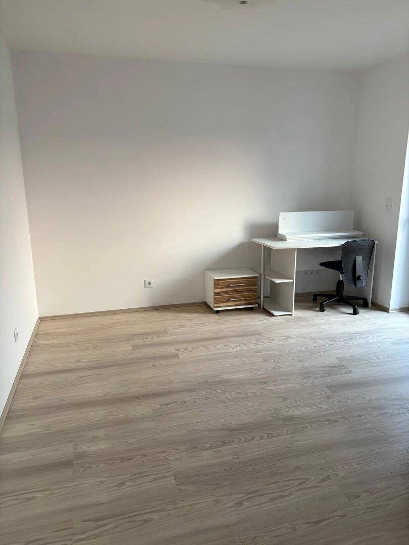 Funktional eingerichtetes Arbeitszimmer mit hellem Laminatboden und einem Schreibtisch.