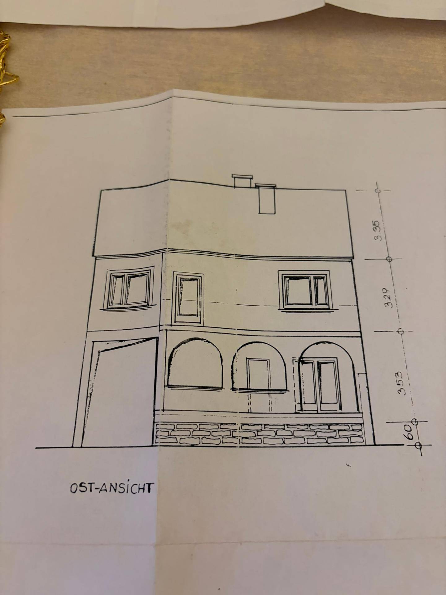 Architektonische Zeichnung einer Hausfassade mit Fenstern und Garagentor.