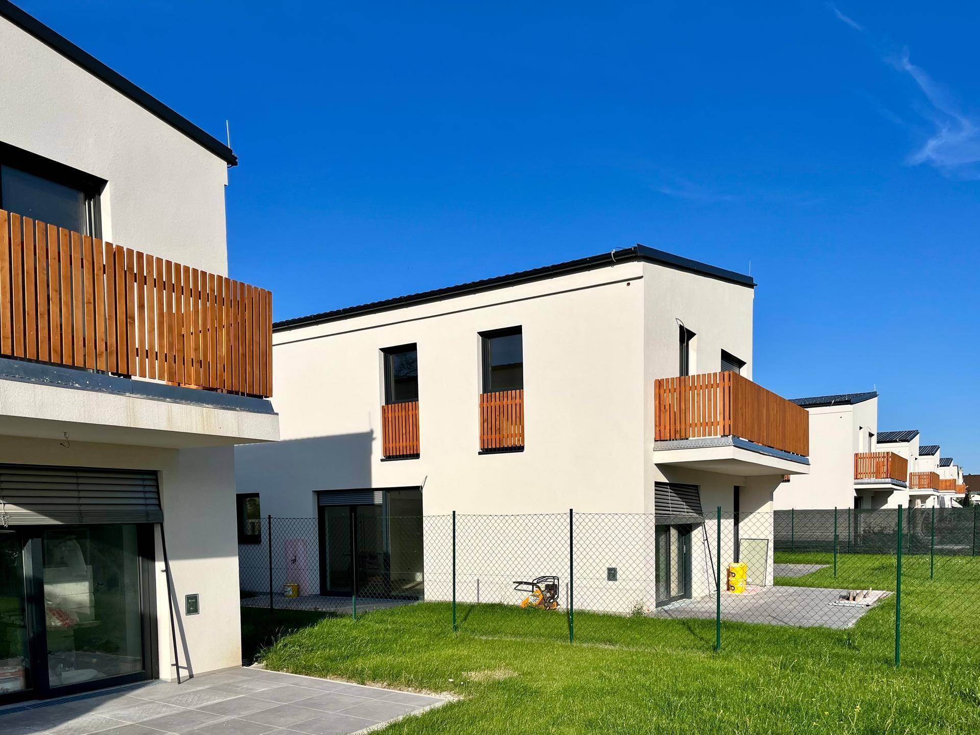 Nahaufnahme von zwei modernen Reihenhäusern mit kleinen Gärten und Holzbalustraden.
