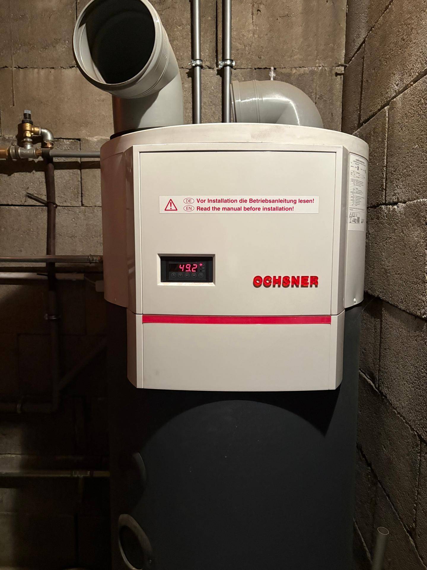 Heizungsraum mit Warmwasserbereiter und technischen Installationen im Kellerbereich.