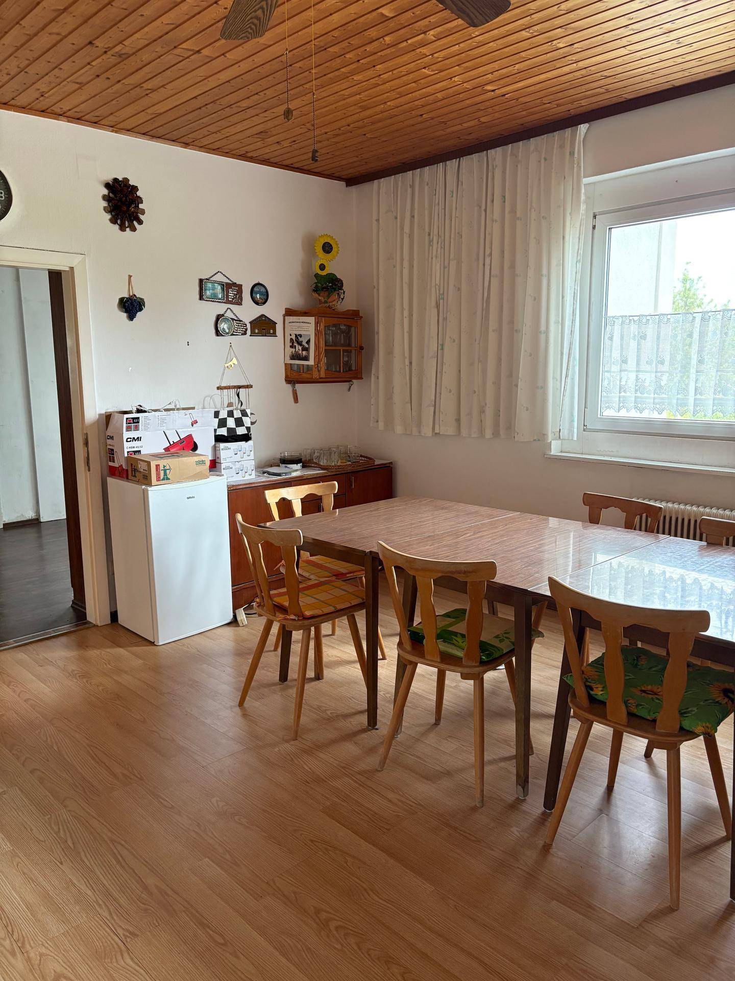 Gemütliches Esszimmer mit großem Holztisch, Holzdecke und hellem Laminatboden.