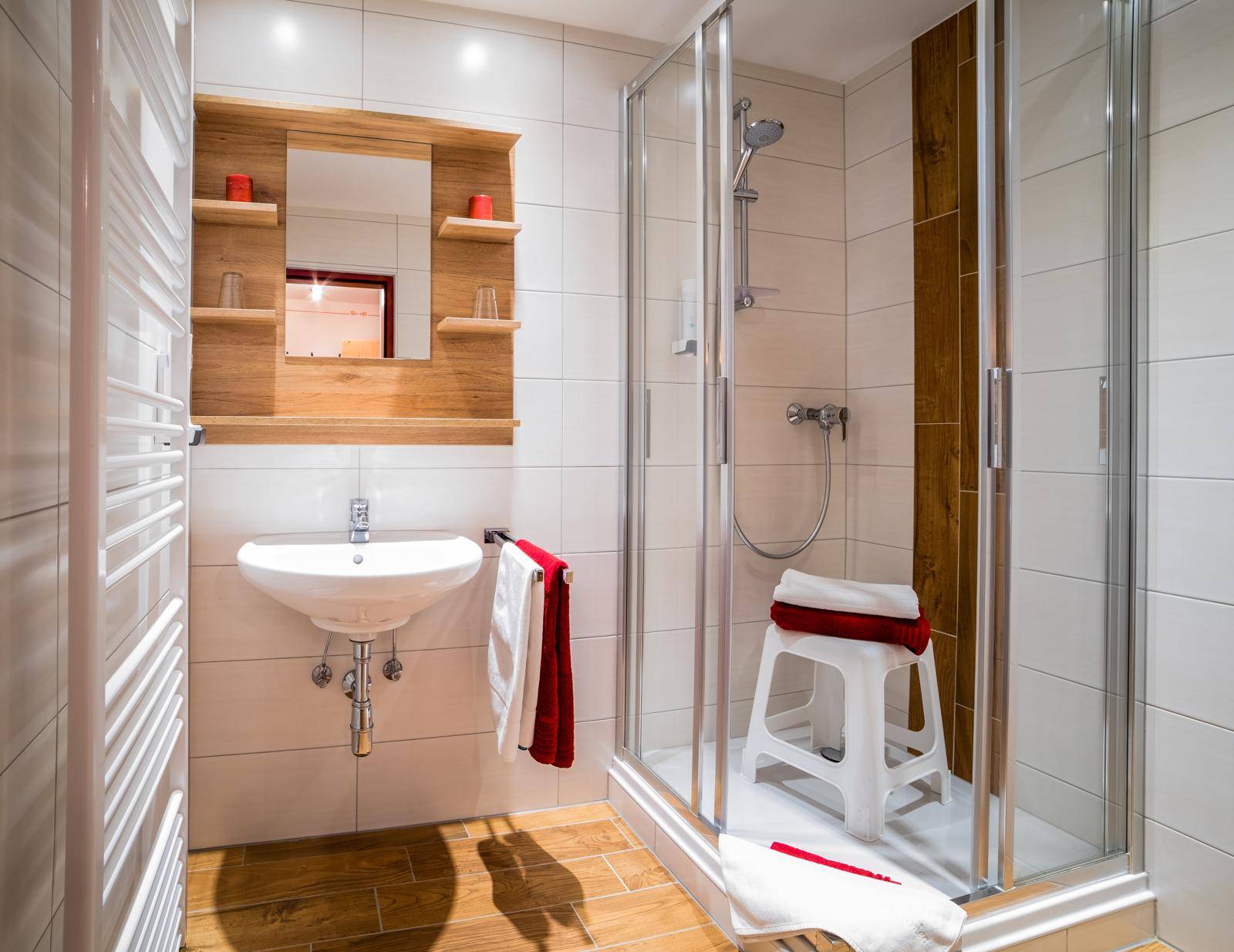 Helles Badezimmer mit Duschkabine, Einzelwaschbecken und Holzdetails.