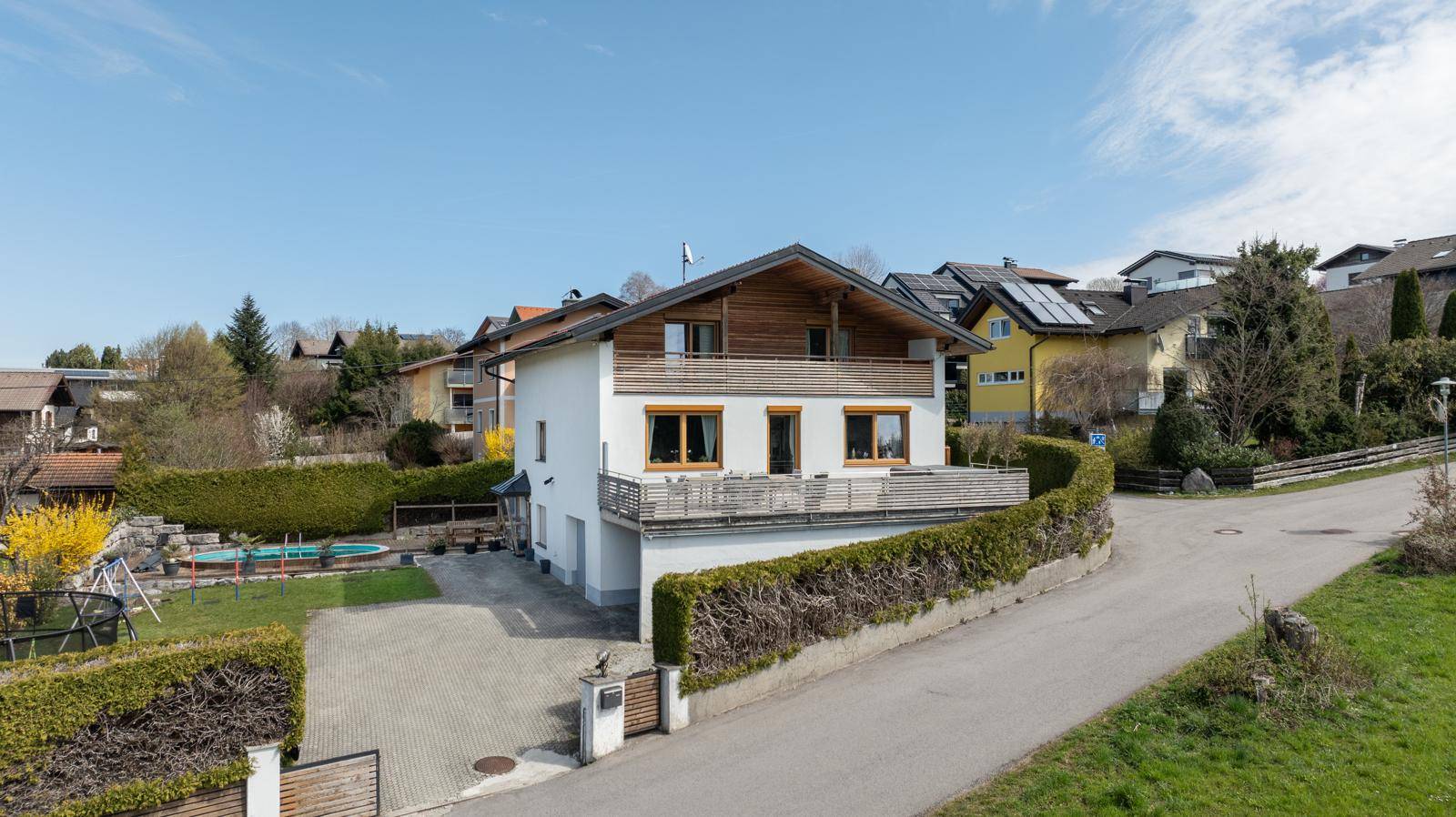 Luftaufnahme eines Einfamilienhauses mit Garten, Pool, Trampolin und Spielplatz in ländlicher Umgebung.
