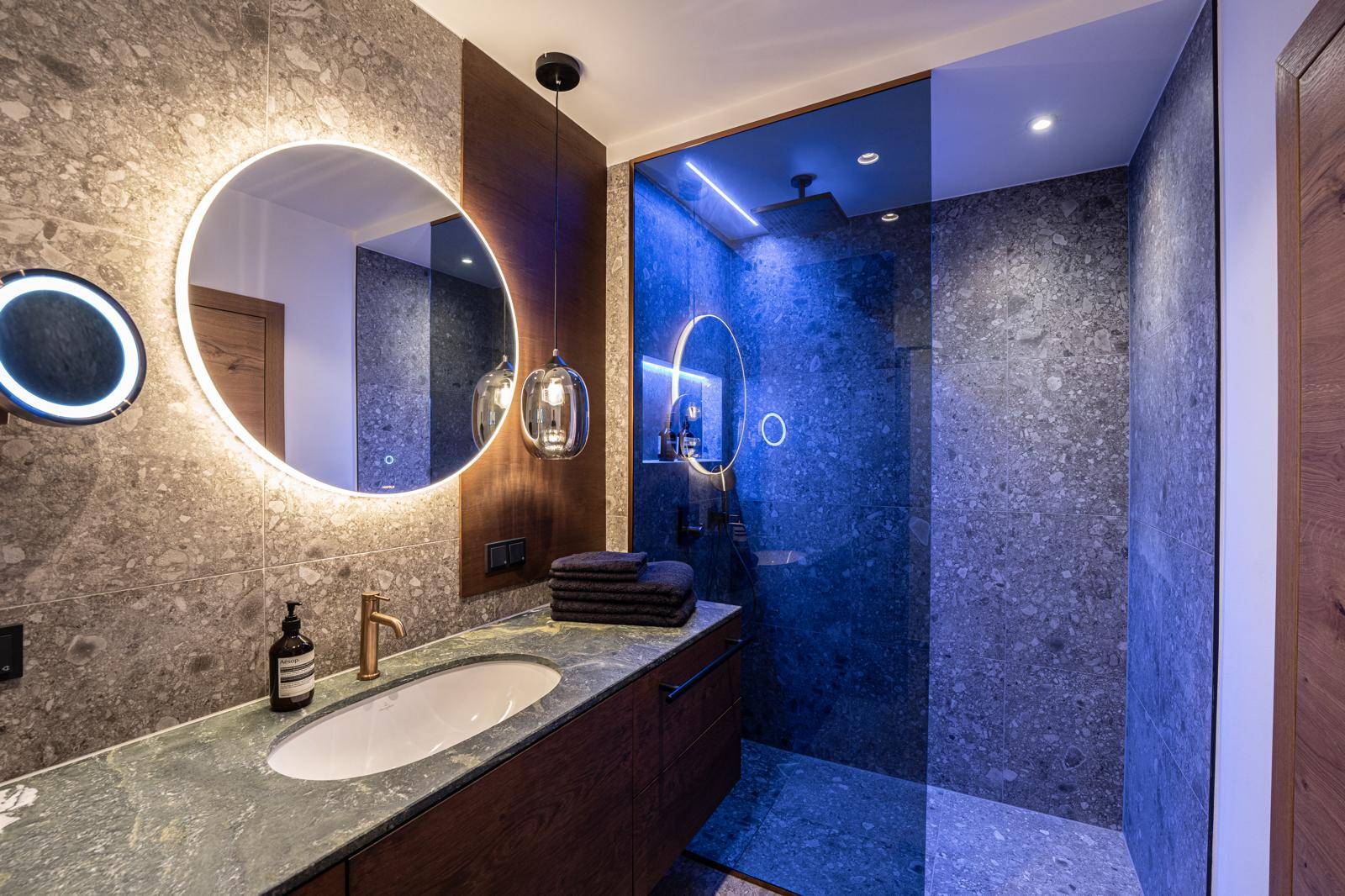 Modernes Badezimmer mit großer Dusche, stilvollem Waschtisch und beleuchtetem Spiegel.