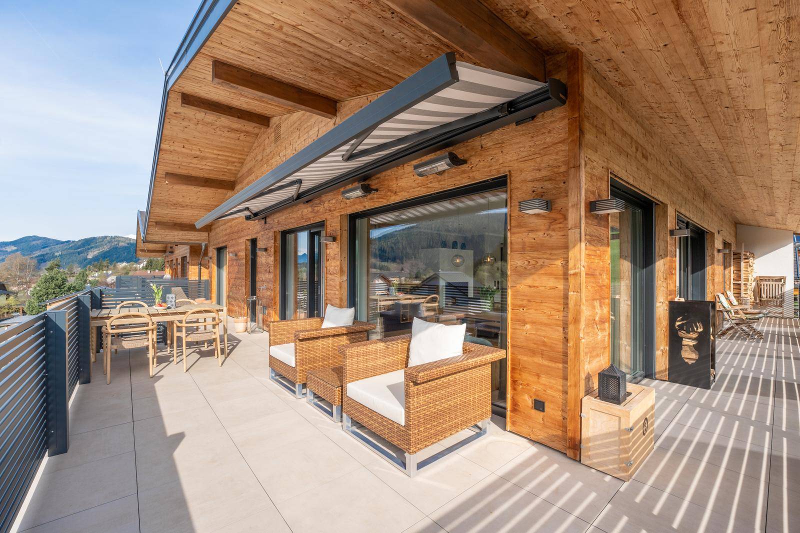 Weitläufige Terrasse mit Holzfassade, bequemen Loungemöbeln und Essbereich.
