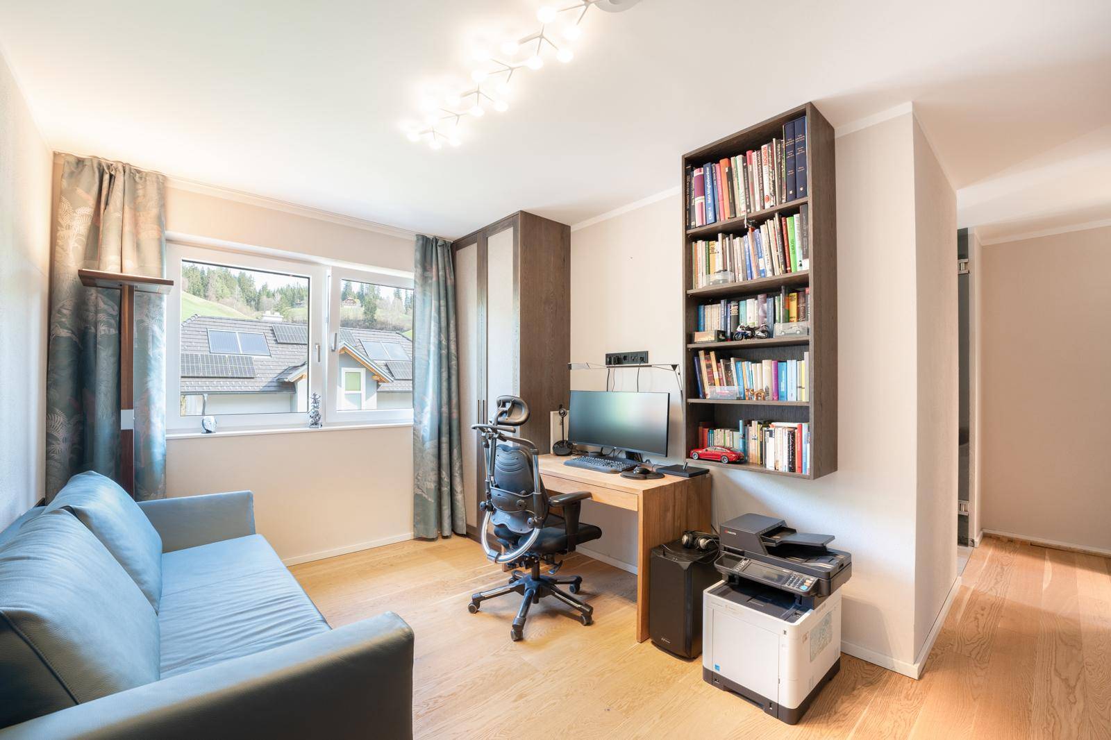 Funktionales Büro mit Schreibtisch, Bücherregal und Sofa, ideal für Home-Office.
