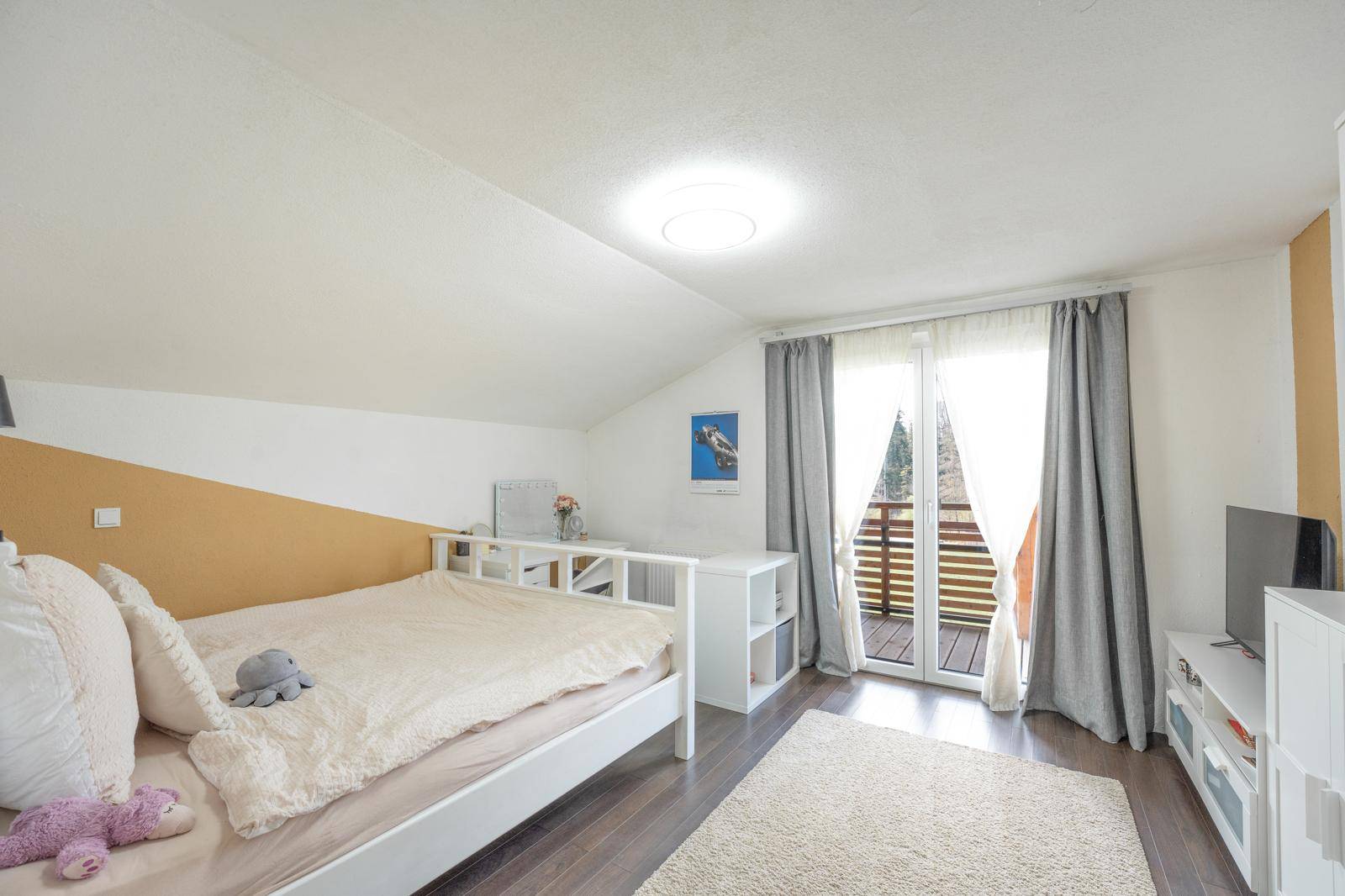 Gemütliches Schlafzimmer mit Balkonzugang, Holzboden und Schreibtischbereich unter der Dachschräge.