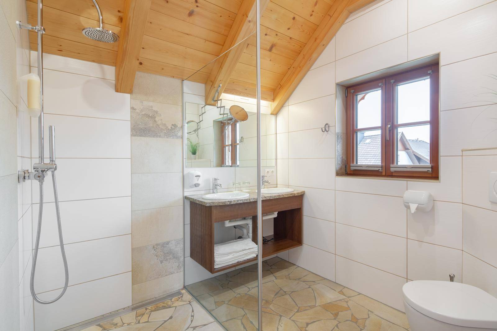 Modernes Badezimmer mit begehbarer Dusche, Doppelwaschbecken und schräger Holzdecke.