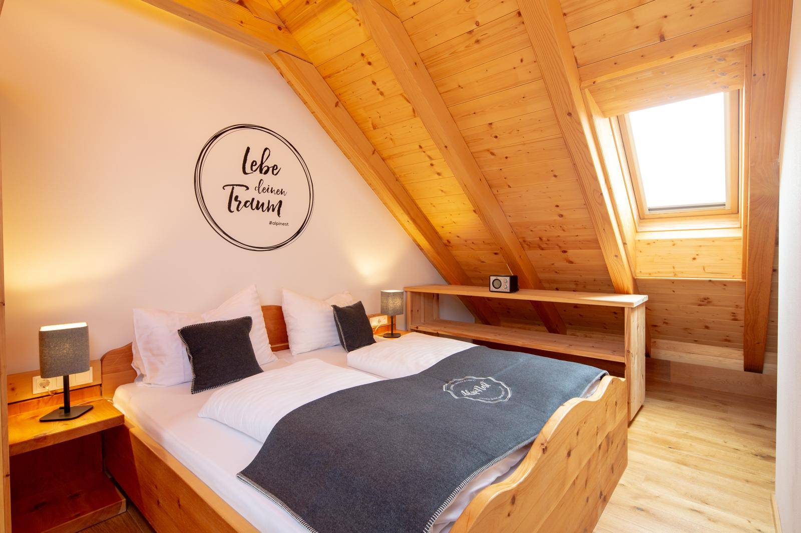 Gemütliches Schlafzimmer mit Doppelbett, Holzvertäfelung und Dachfenster für natürliches Licht.