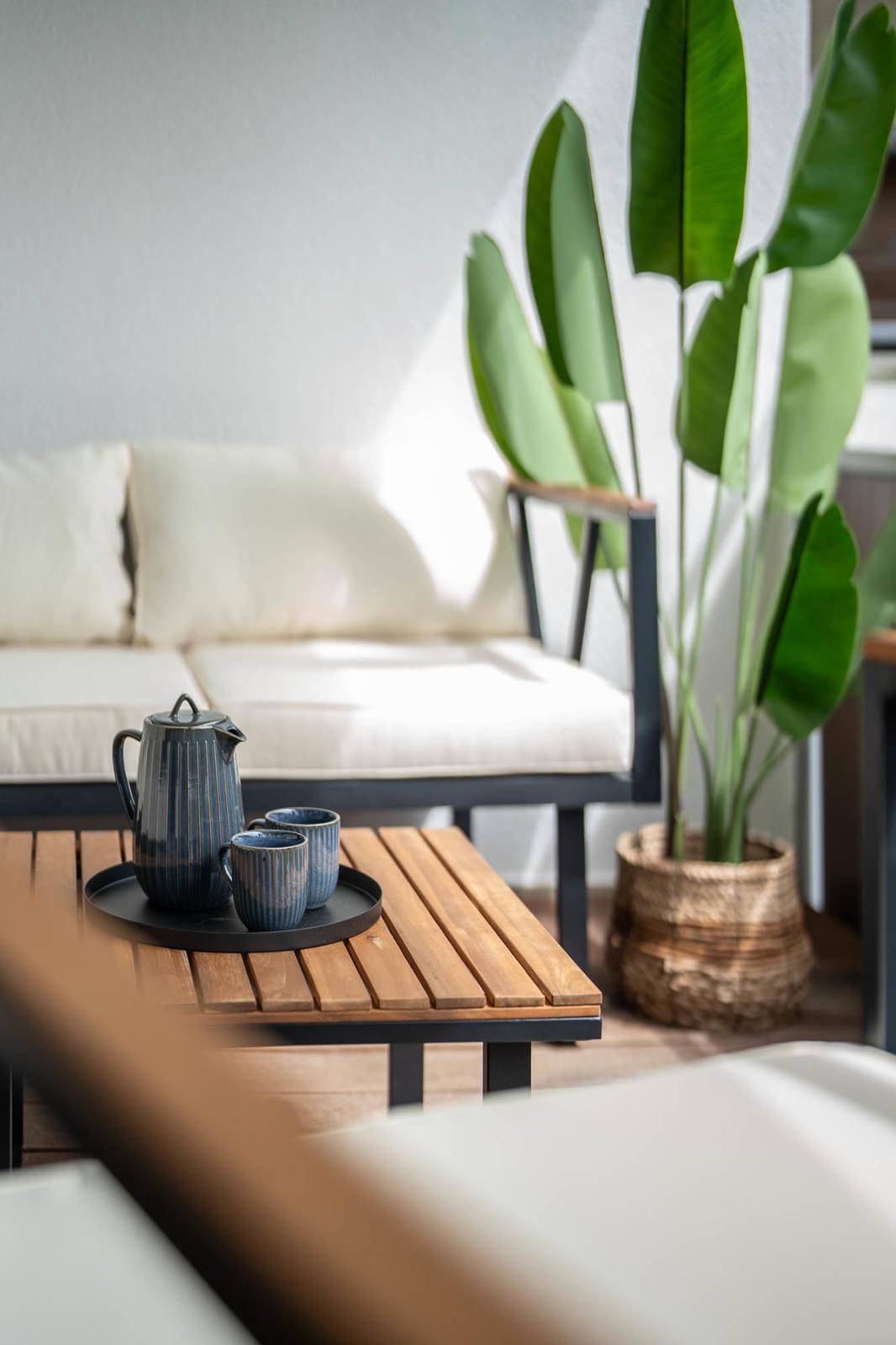 Detailaufnahme der Balkonmöbel mit Kaffeekanne und Zimmerpflanze.