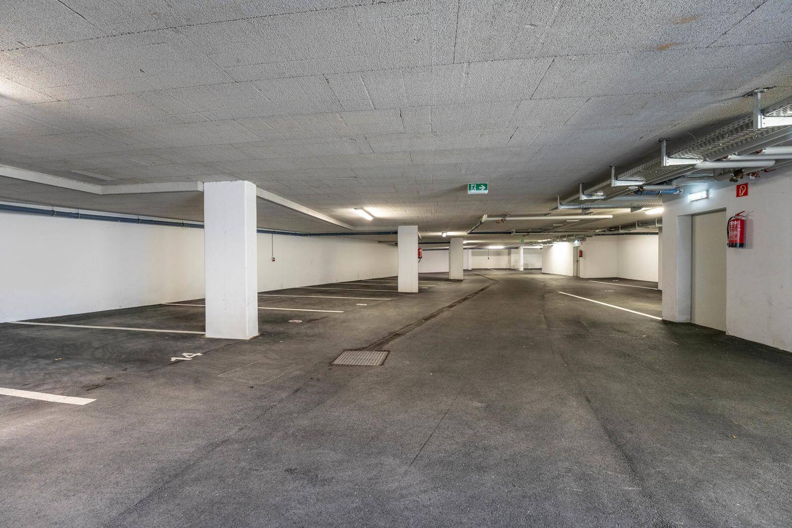 Geräumige Tiefgarage mit vielen freien Stellplätzen, Betonpfeilern und guter Beleuchtung.